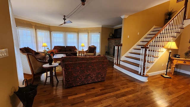 living area featuring a fireplace, baseboards, ornamental molding, stairway, and dark wood-style floors