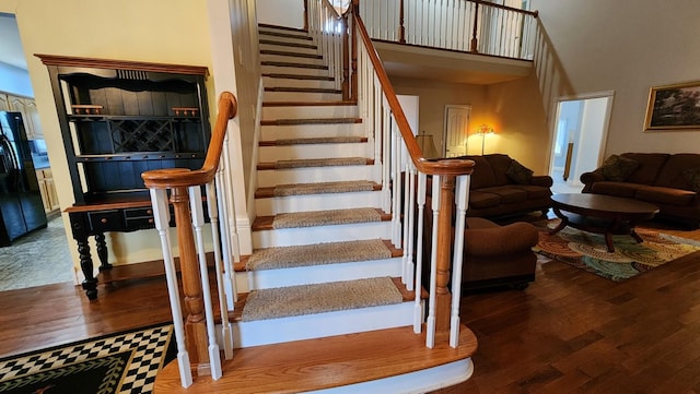 stairway with a towering ceiling and wood finished floors