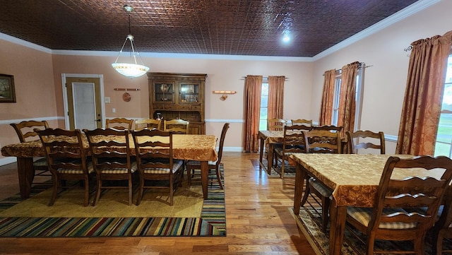 dining space featuring an ornate ceiling, ornamental molding, and light wood finished floors