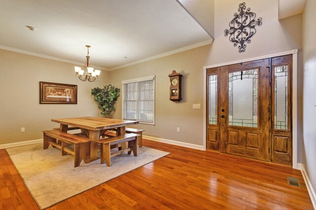 dining space with an inviting chandelier, wood finished floors, visible vents, and baseboards