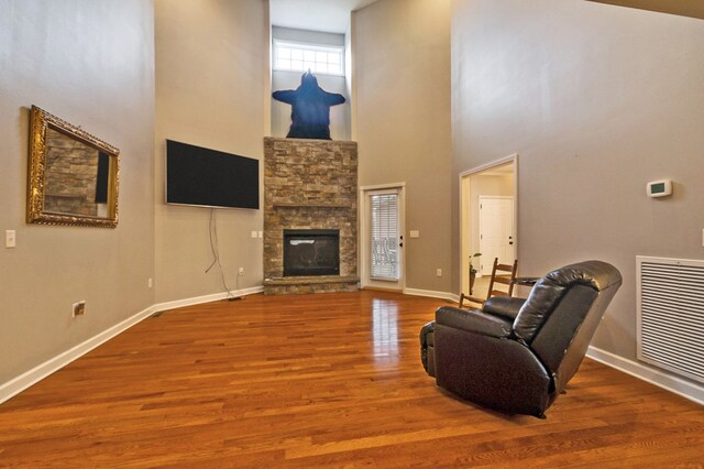 living area featuring baseboards, a fireplace, visible vents, and wood finished floors