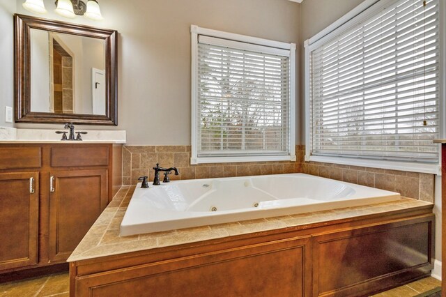 full bath featuring plenty of natural light, vanity, and a tub with jets