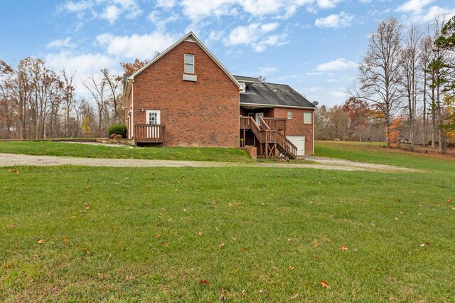 rear view of property with brick siding, a yard, an attached garage, a deck, and stairs