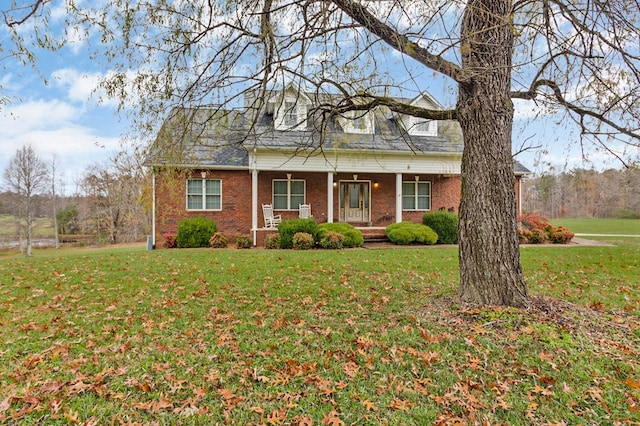 cape cod-style house with brick siding, a porch, and a front yard