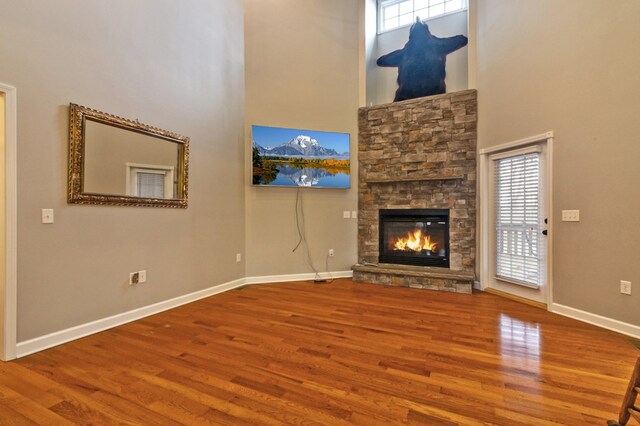 unfurnished living room with a healthy amount of sunlight, a fireplace, baseboards, and wood finished floors