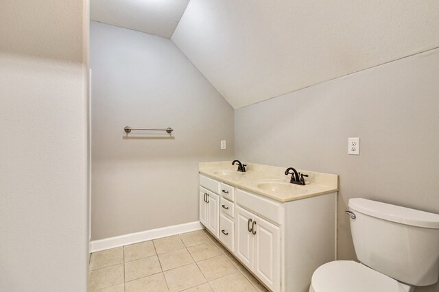 bathroom featuring toilet, tile patterned flooring, a sink, and lofted ceiling