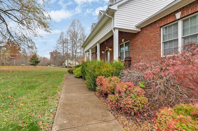 view of property exterior featuring brick siding and a lawn