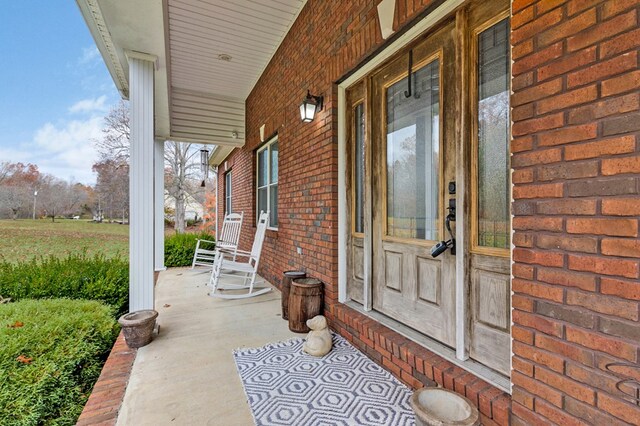 property entrance featuring covered porch and brick siding