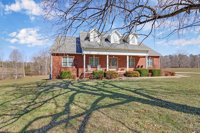 cape cod home with covered porch, a front lawn, and brick siding