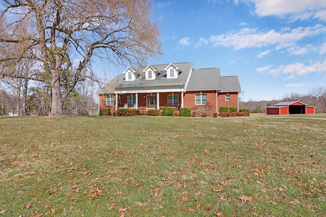 new england style home featuring an outbuilding, a pole building, a front lawn, and brick siding