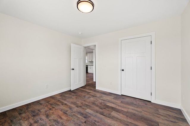 unfurnished bedroom with dark wood finished floors and baseboards