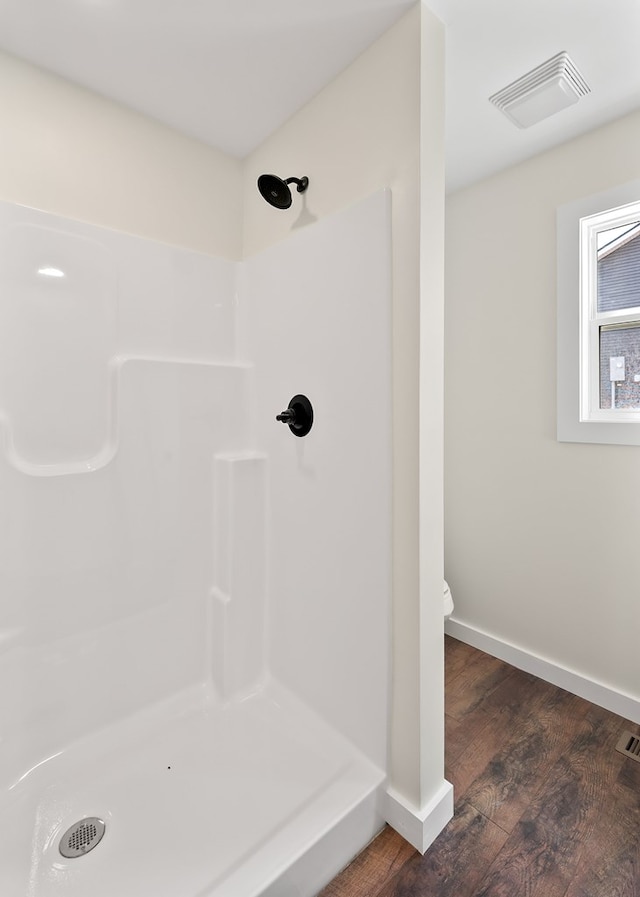 full bath featuring toilet, wood finished floors, visible vents, baseboards, and walk in shower