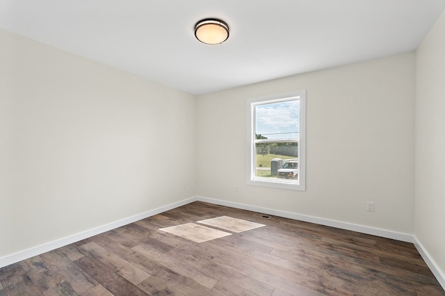 spare room featuring visible vents, baseboards, and dark wood finished floors