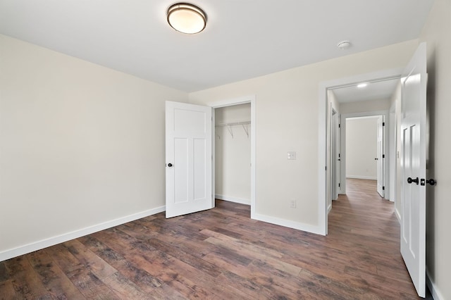 unfurnished bedroom with dark wood-style floors, a closet, and baseboards