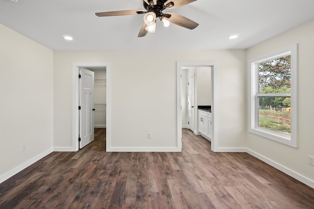 unfurnished bedroom featuring a spacious closet, baseboards, dark wood-style flooring, and recessed lighting