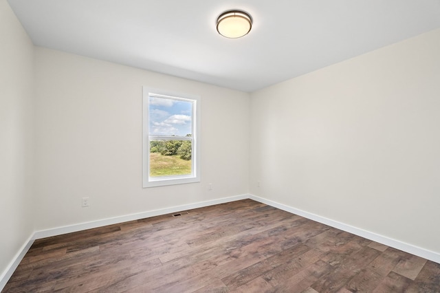 unfurnished room with dark wood-style floors, visible vents, and baseboards