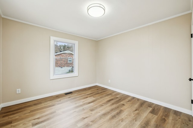 spare room featuring light wood-type flooring, visible vents, crown molding, and baseboards