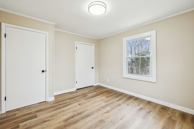 unfurnished bedroom with light wood finished floors, ornamental molding, and baseboards