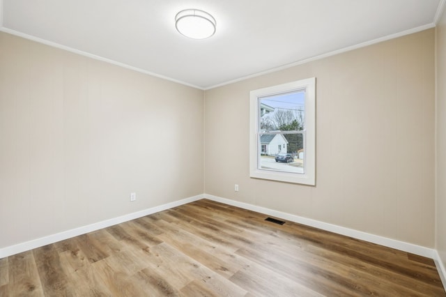 unfurnished room with baseboards, light wood-style flooring, visible vents, and crown molding