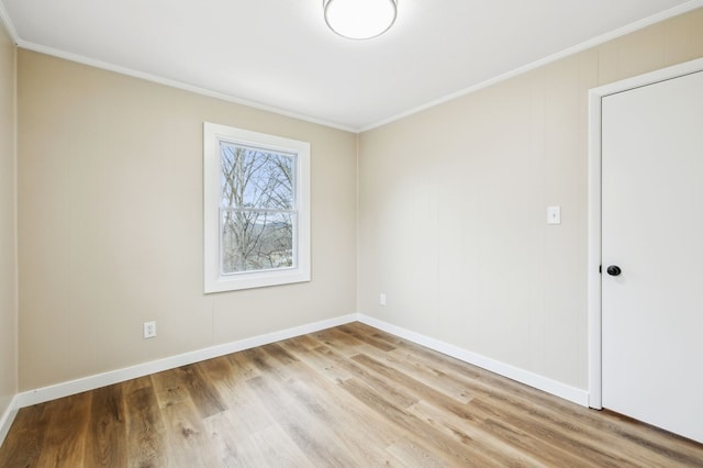 empty room with light wood finished floors, baseboards, and crown molding