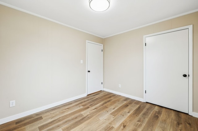 empty room with baseboards, crown molding, and light wood finished floors