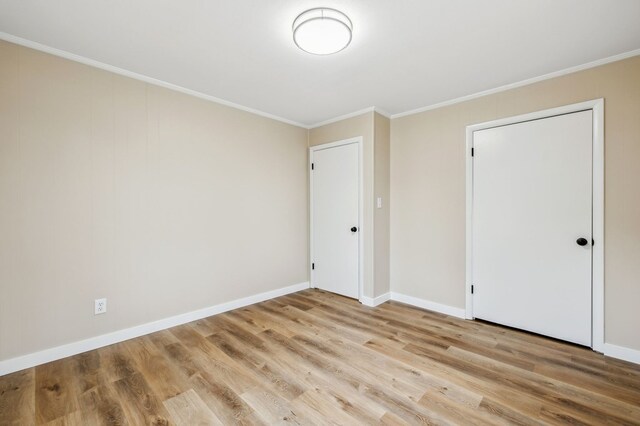 unfurnished bedroom with ornamental molding, light wood-style flooring, and baseboards