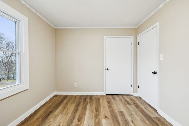 unfurnished room with ornamental molding, baseboards, and wood finished floors