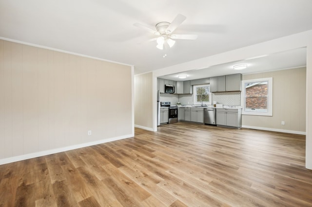 unfurnished living room with a sink, light wood-style floors, ceiling fan, and crown molding