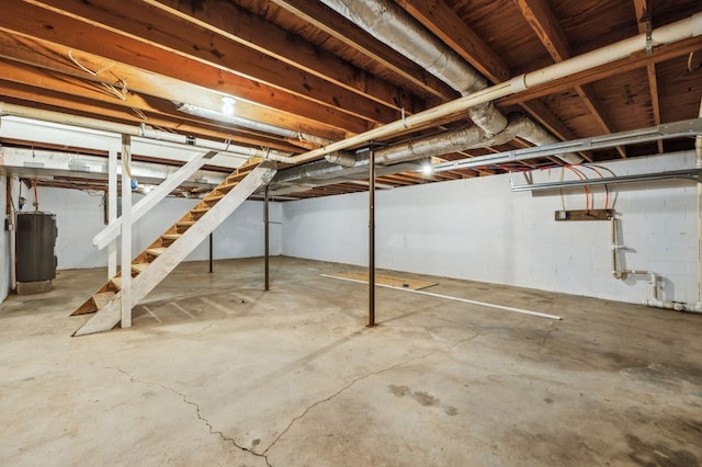 unfinished basement featuring stairway and electric water heater