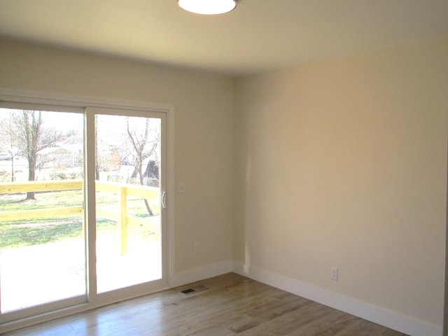 spare room featuring visible vents, baseboards, and wood finished floors