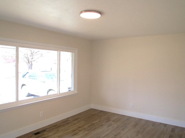 spare room featuring visible vents, baseboards, and wood finished floors