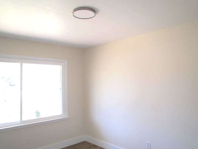 unfurnished room with baseboards and wood finished floors