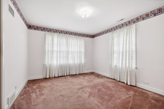 carpeted empty room featuring visible vents and baseboards