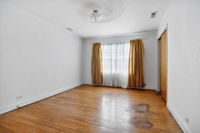 empty room featuring light wood finished floors, baseboards, and visible vents