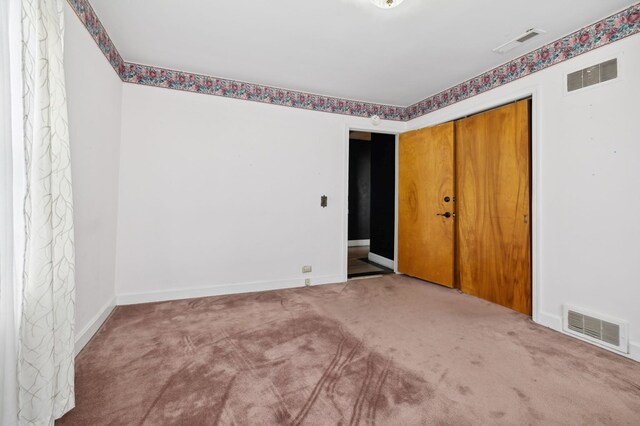 unfurnished room with carpet, visible vents, and baseboards