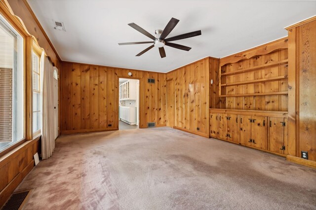 unfurnished room with wooden walls, visible vents, and light colored carpet