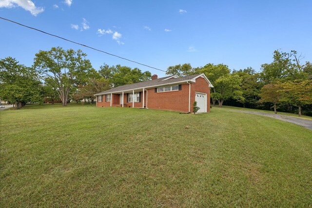 view of front of house featuring an attached garage, driveway, brick siding, and a front yard