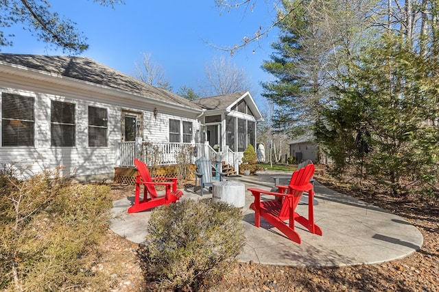 exterior space featuring a patio area, a fire pit, and a sunroom