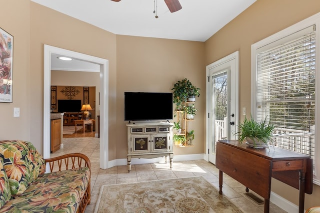 living area with light tile patterned floors, baseboards, and ceiling fan