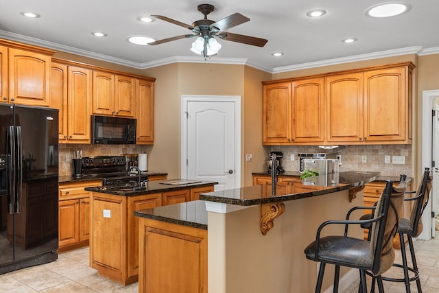 kitchen featuring a kitchen bar, black appliances, an island with sink, and ornamental molding