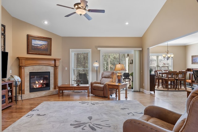 living room with recessed lighting, light wood finished floors, a tiled fireplace, and vaulted ceiling