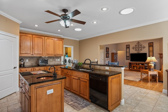 kitchen with dishwasher, washing machine and dryer, a center island with sink, and a sink