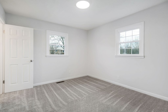 empty room with carpet flooring, visible vents, and baseboards