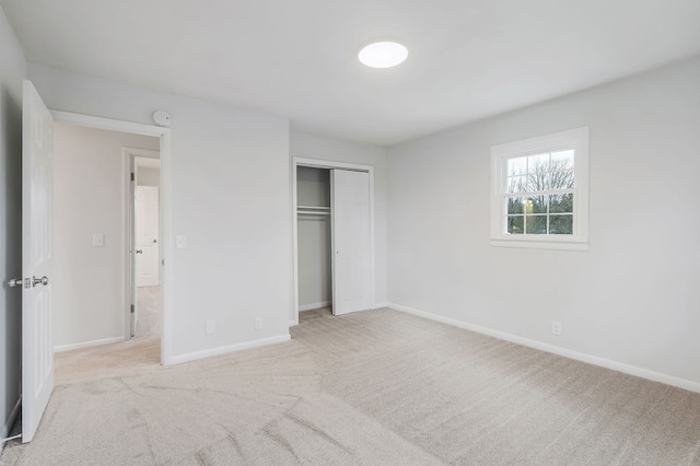 unfurnished bedroom with baseboards, a closet, and light colored carpet