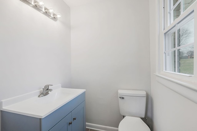 half bathroom with vanity, toilet, and baseboards