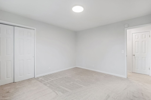 unfurnished bedroom featuring baseboards, a closet, and light colored carpet