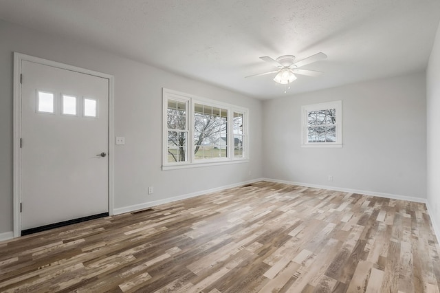 entryway featuring a ceiling fan, baseboards, visible vents, and wood finished floors