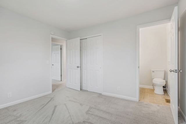 unfurnished bedroom with a closet, light colored carpet, and baseboards