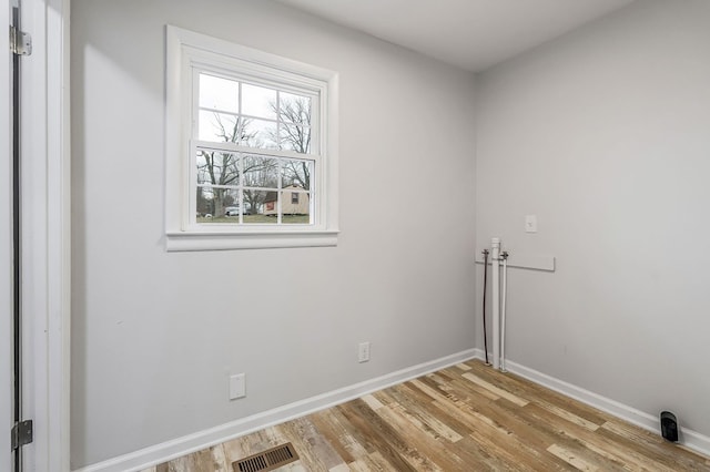 spare room with light wood-style floors, visible vents, and baseboards