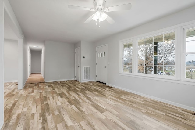 interior space featuring visible vents, ceiling fan, light wood-style flooring, and baseboards